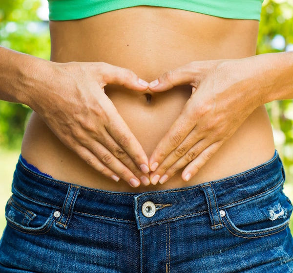 Hands in heart shape over womans belly