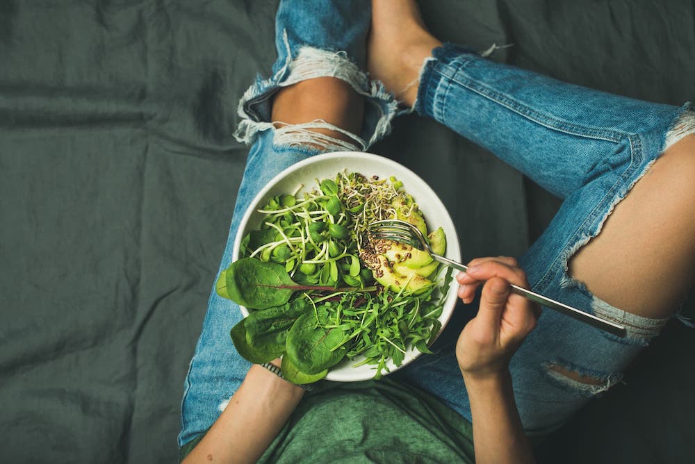 Healthy people don't diet. Woman eating a vegan bowl with quinoa, spinach, avocado, and greens.