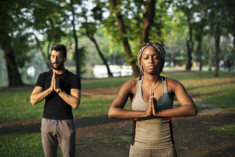 Healthy people aren't stressed. 2 people in a park doing meditation and yoga. 